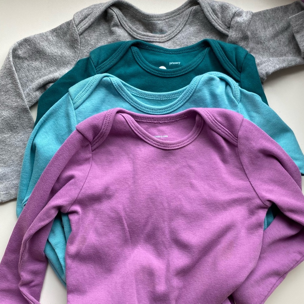 Four Primary signature long sleeve baby suits in purple, pool, spruce, and gray.